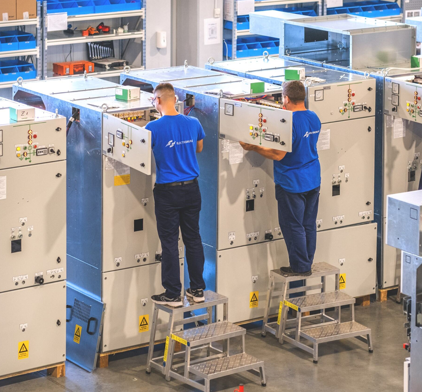 Muncitori care lucrează la echipamente electrice